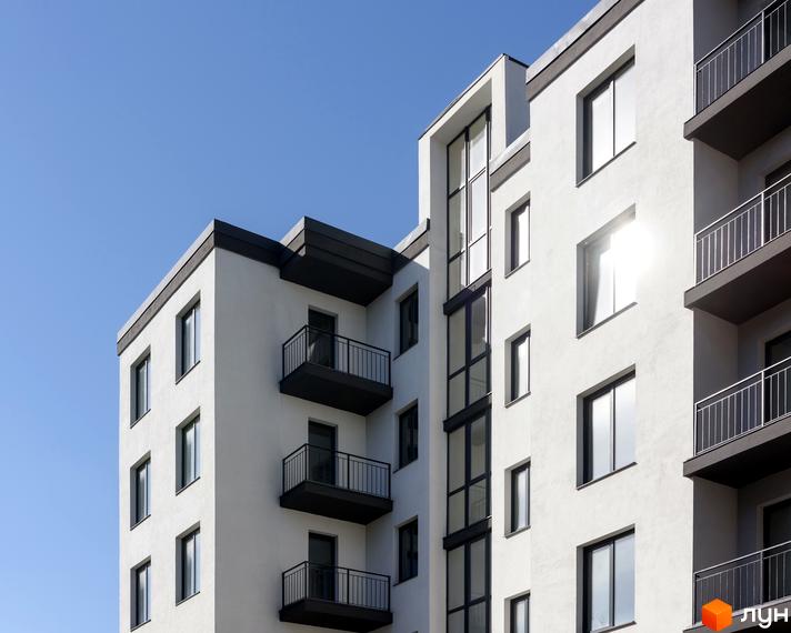 Зовнішній вигляд новобудови на вулиці Козачука, 27а, з балконами та великими вікнами на фоні блакитного неба.