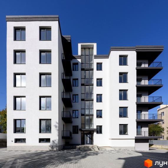 Зовнішній вигляд новобудови на вул. Козачука, 27а, з білими стінами та темними балконами. Перед будинком розташований вимощений двір.