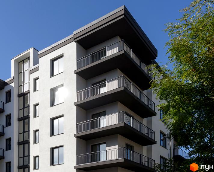 Новобудова на вулиці Козачука, 27а, з балконами та вікнами на тлі блакитного неба та зелені.