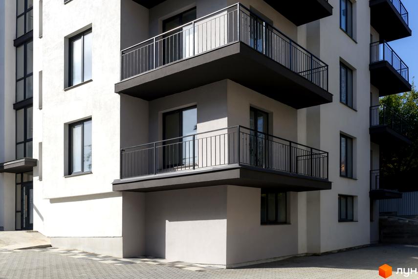 Зовнішній вигляд новобудови на вул. Козачука, 27а, з балконами та вікнами. Навколо будинку розташована прибудинкова територія з бруківкою.