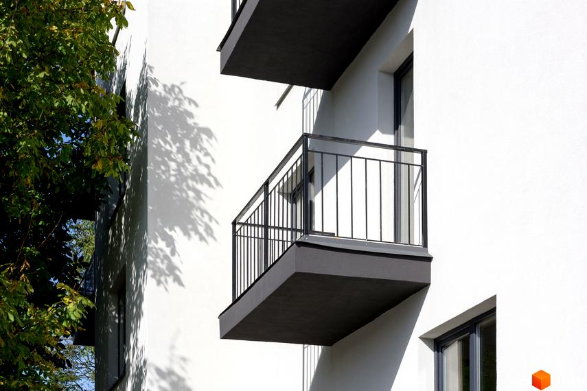 Зовнішній вигляд новобудови вул. Козачука, 27а, з балконами та вікнами. Навколо будівлі зелені дерева та тіні від листя.