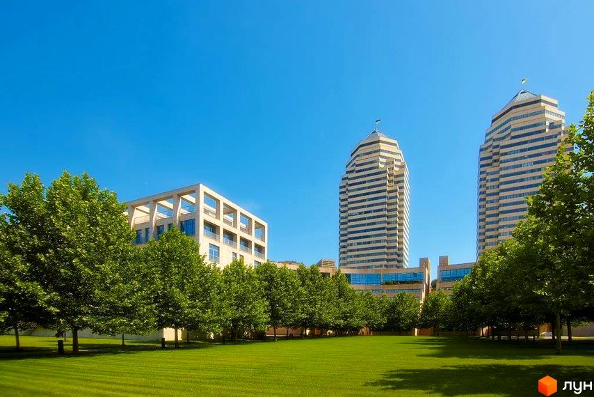 Житловий комплекс Фестивальний з двома сучасними будинками на фоні зеленого газону та дерев.