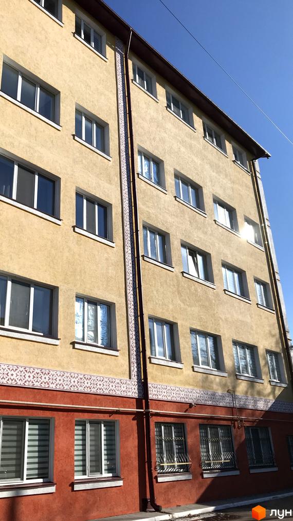 Фасад житлового комплексу на вул. Вокзальна (Юрія Гагаріна), 54а. Будинок має жовтий колір стін та червону нижню частину, з численними вікнами.