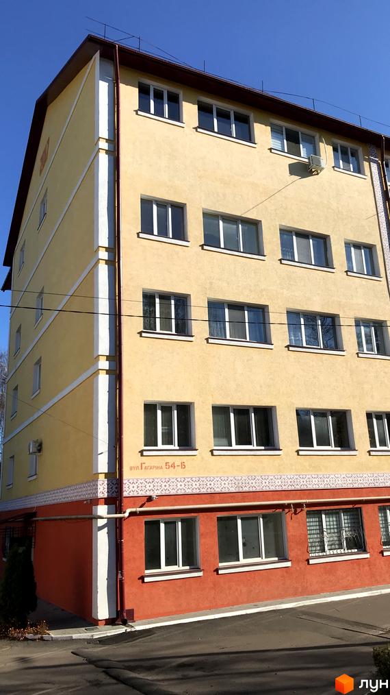 Житловий комплекс на вулиці Гагаріна, 54-15. Жовтий багатоповерховий будинок з червоним цоколем та білими декоративними елементами. Навколо будинку асфальтована дорога та зелені насадження.