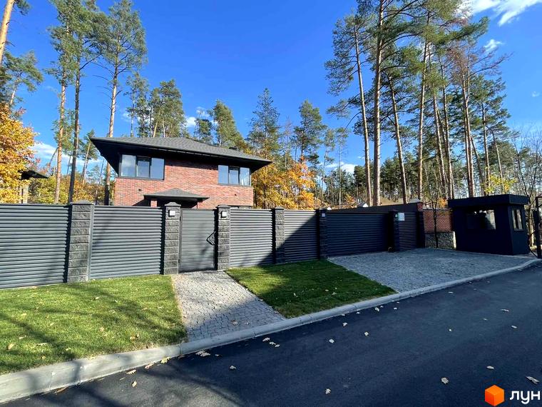 Котеджне містечко Лісові Плюти: цегляний будинок з темним дахом, огороджена територія з воротами та доглянутим газоном.