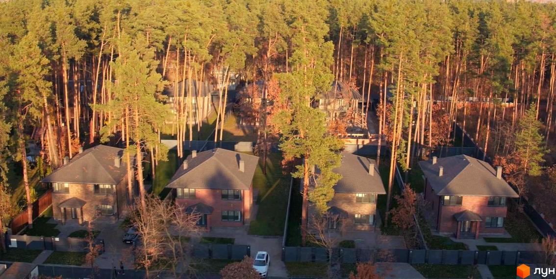 Котеджне містечко КМ Лісові Плюти. Цегляні двоповерхові будинки з темними дахами, розташовані серед соснового лісу з доглянутими прибудинковими територіями.