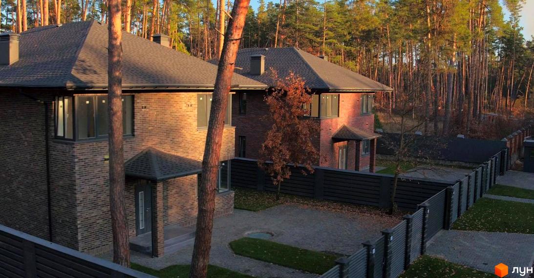 Котеджне містечко Лісові Плюти. Цегляні будинки з темними дахами та парканом на тлі лісу.