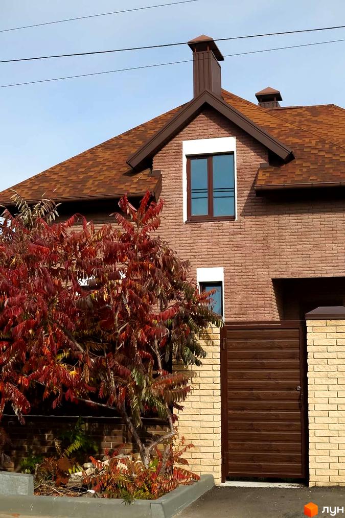 Котеджне містечко КМ Барвіта: цегляний будинок з коричневим дахом та дверима, поруч дерево з червоним листям.