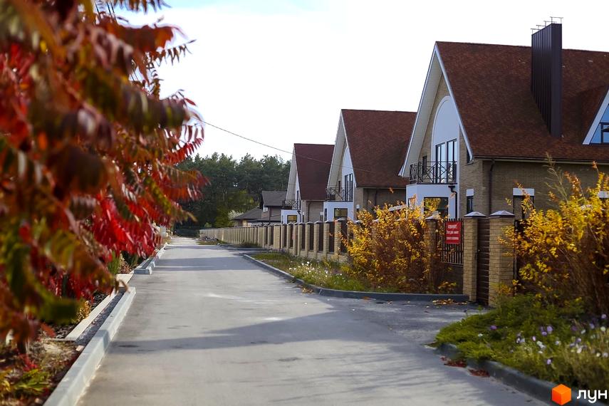 Котеджне містечко Барвіта: фасади будинків з червоним дахом та прибудинкова територія з деревами та парканом. Фото новобудови.