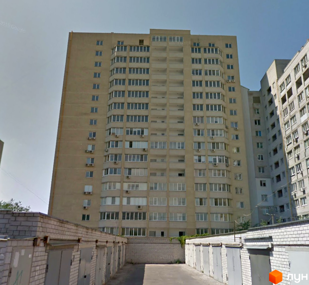 Житловий комплекс Георгіївський: багатоповерховий будинок світло-коричневого кольору з білими вікнами. Перед ним розташовані ряди цегляних гаражів.