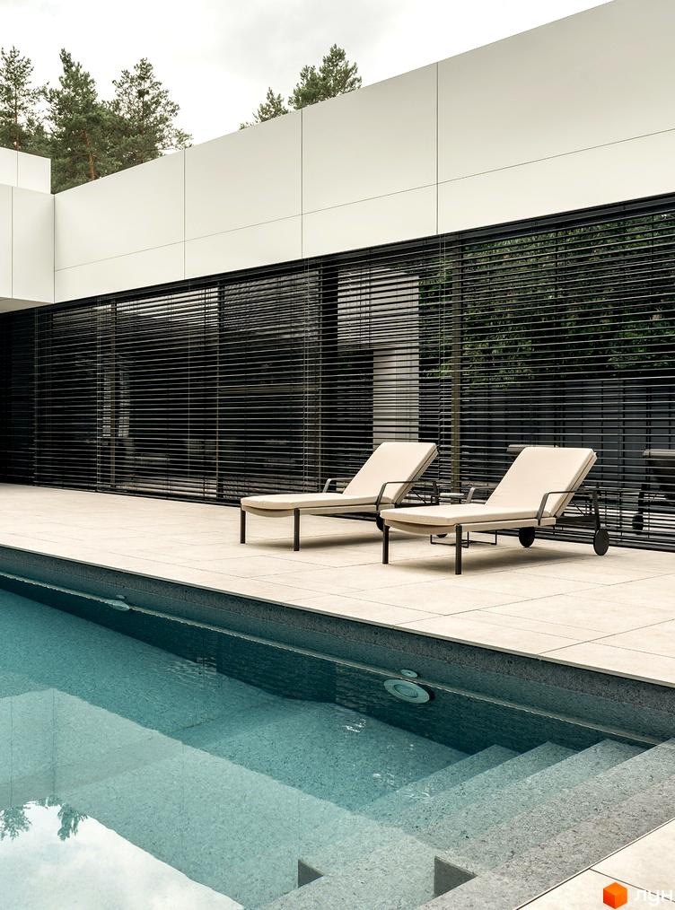 Котеджне містечко 3L Residences: білий фасад будинку з великими чорними жалюзі. На прибудинковій території басейн та зона відпочинку з лежаками.