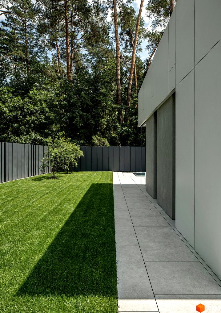 Котеджне містечко KM 3L Residences: сучасний фасад будинку з сірих панелей та доглянута прибудинкова територія з газоном та огорожею.