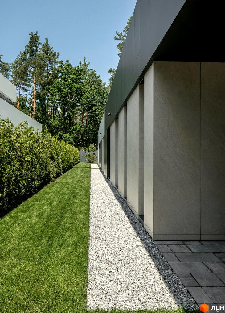 Зовнішній вигляд будинку в Котеджному містечку 3L Residences з прибудинковою територією, де є газон, декоративні кущі та доріжка з гравію.