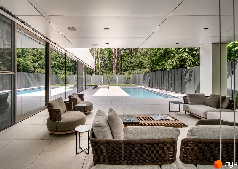 Вид на басейн та зону відпочинку на терасі Котеджного містечка 3L Residences. На задньому плані зелені дерева та сіра огорожа.