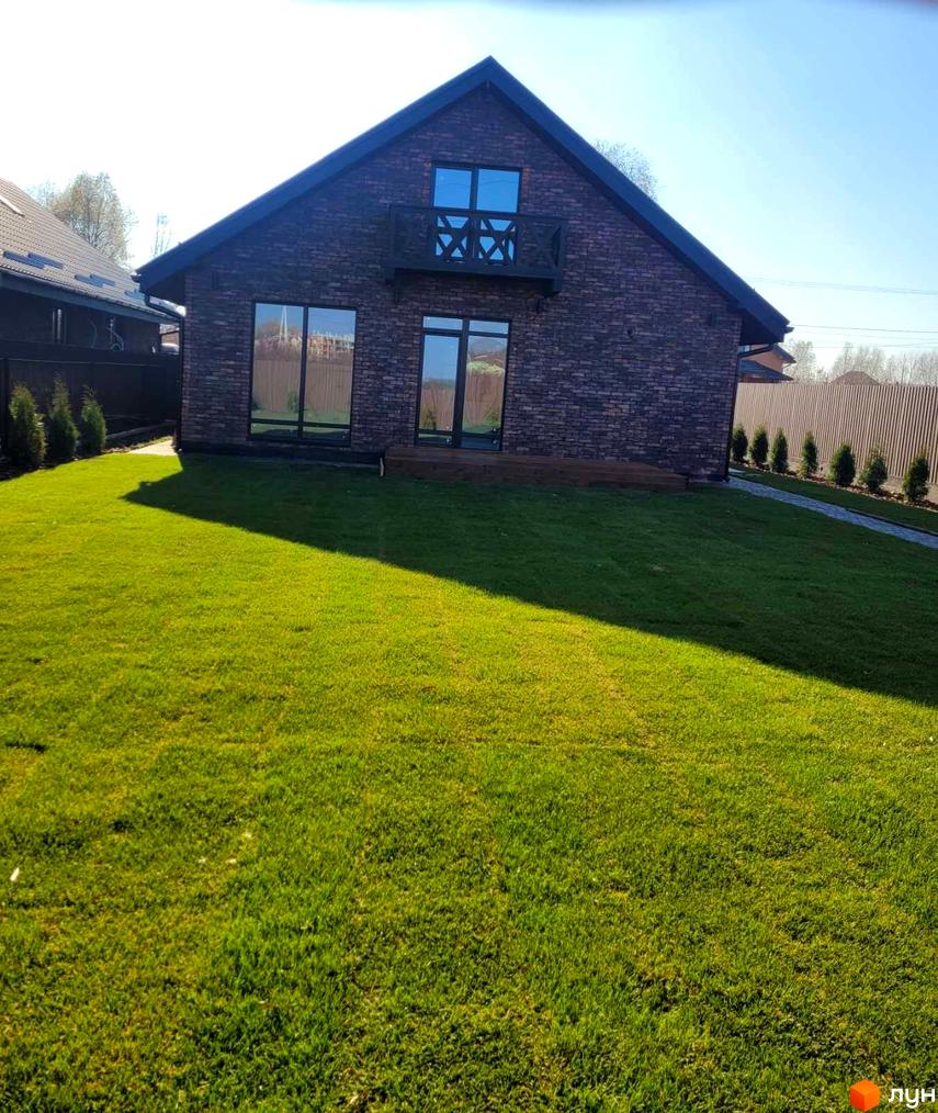 Зображення будинку в Котеджному містечку Одноповерховий Київ - Шевченкове. Вигляд фасаду будинку та зеленого газону перед ним.