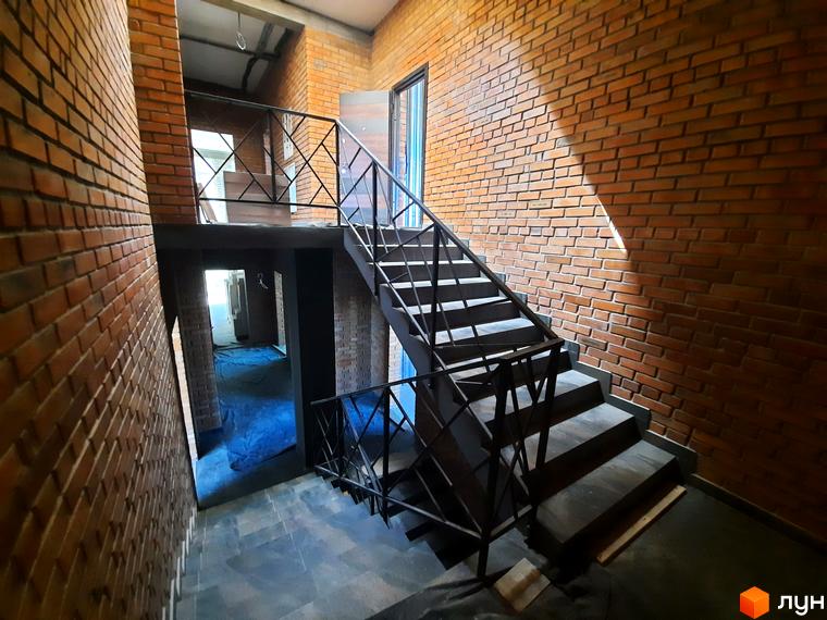 Інтер'єр Житлового комплексу Loft з цегляними стінами та сходами з металевими перилами. Вигляд внутрішнього оздоблення будинку.