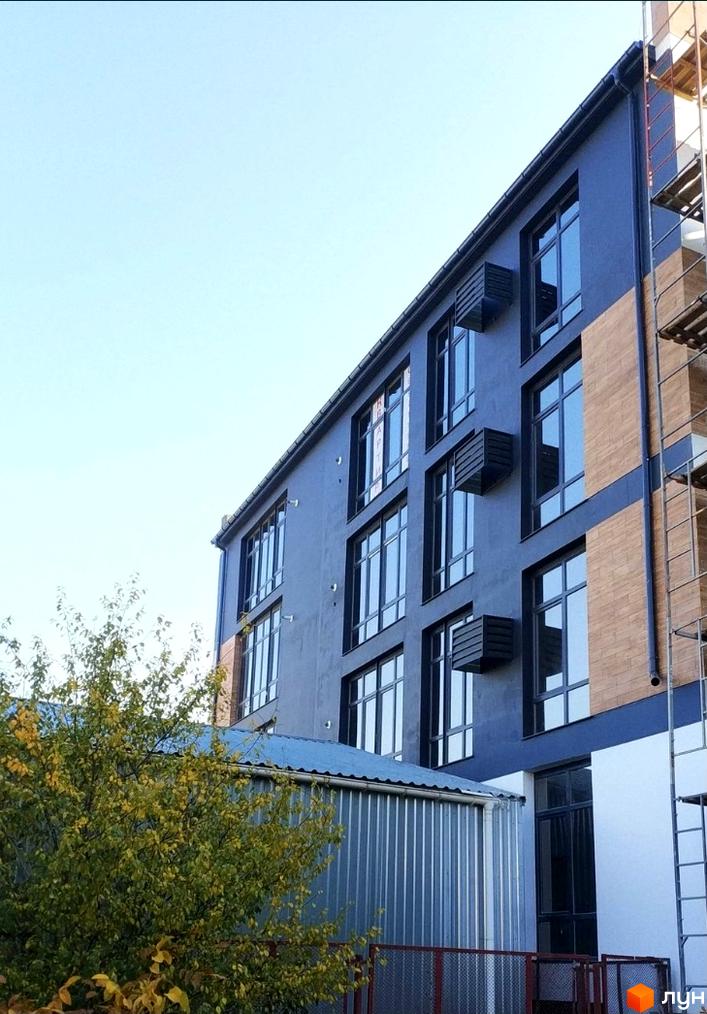 Зовнішній вигляд будинку в Житловому комплексі Loft з великими вікнами. Поруч розташована прибудинкова територія з деревами.