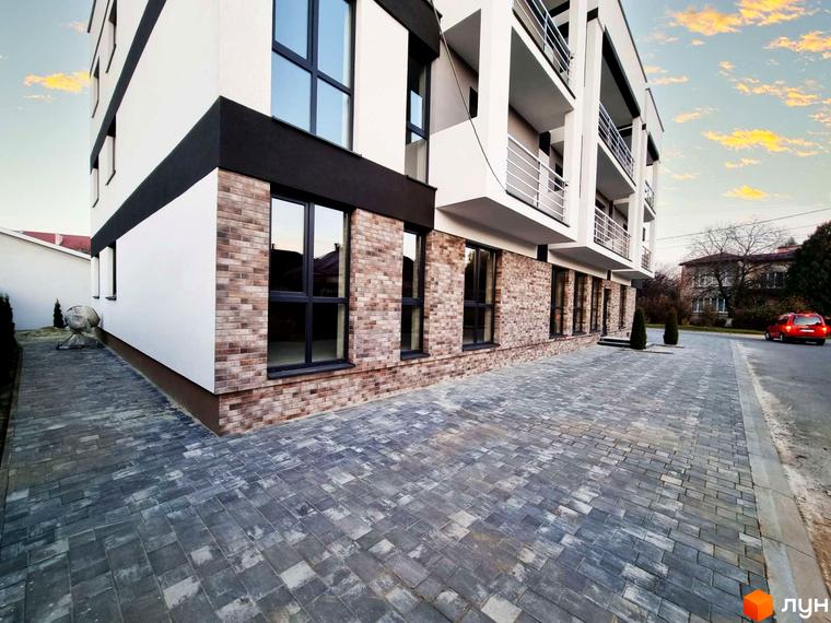 Зовнішній вигляд Житлового комплексу Преміум Хаус з оздобленням фасаду цеглою. На передньому плані викладена бруківкою прибудинкова територія.