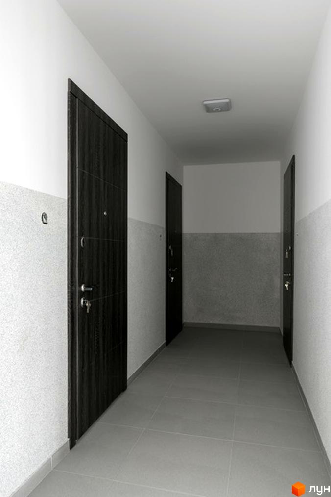 Вхідна група житлового комплексу на вулиці Козачука, 27а. Коридор з темними дверима та сірою плиткою на стінах та підлозі.