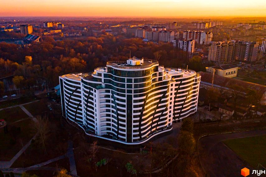 Зображення Житлового комплексу Parus з висоти пташиного польоту. Багатоповерхова будівля з хвилястими балконами та панорамними вікнами, оточена деревами.