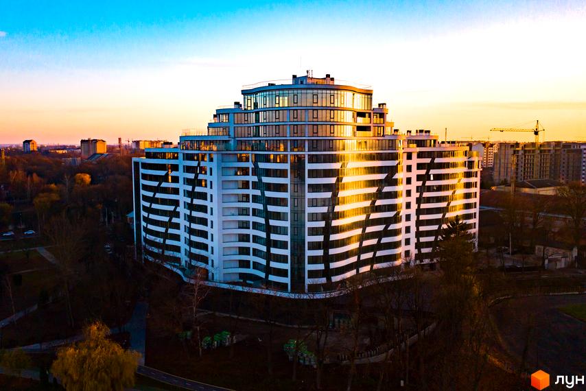 Зображення Житлового комплексу Parus. Багатоповерховий будинок з великою кількістю вікон та балконів, розташований серед дерев.