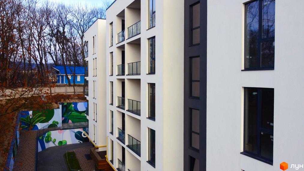 Висотна будівля житлового комплексу Globus Central Park з балконами та великими вікнами. Поряд з будинком розташована прибудинкова територія з графіті.