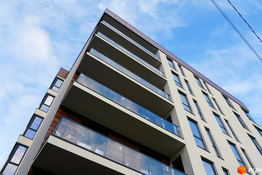 Житловий комплекс Globus Central Park. Фасад будівлі з балконами та скляними огорожами на тлі блакитного неба.