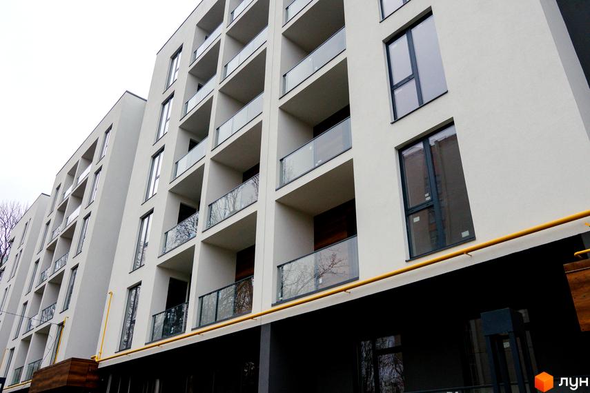 Зовнішній вигляд багатоповерхового будинку ЖК Globus Central Park з балконами зі скляними огорожами. Сіра будівля з великими вікнами на тлі хмарного неба.