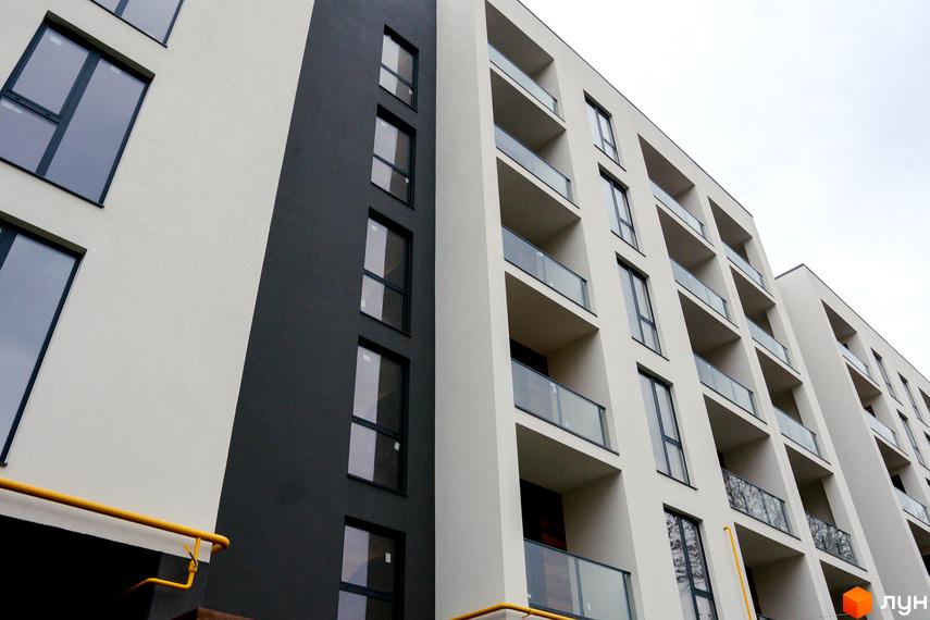 Фасад житлового комплексу Globus Central Park з вікнами та балконами. Зовнішній вигляд новобудови з сірими та білими елементами.