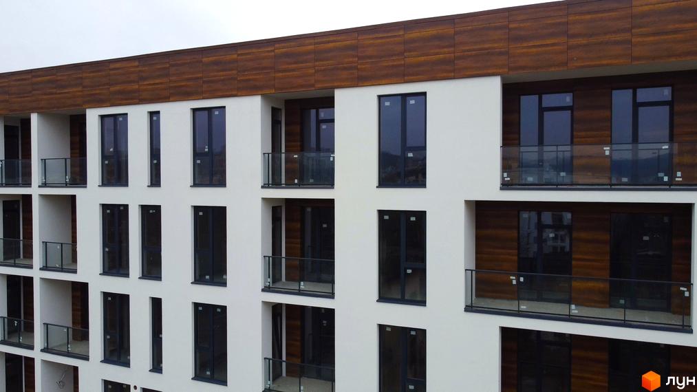 Зовнішній вигляд будівлі житлового комплексу Globus Central Park з балконами, скляними огорожами та панорамними вікнами. Фасад будинку виконаний у світлих тонах з дерев'яними панелями.