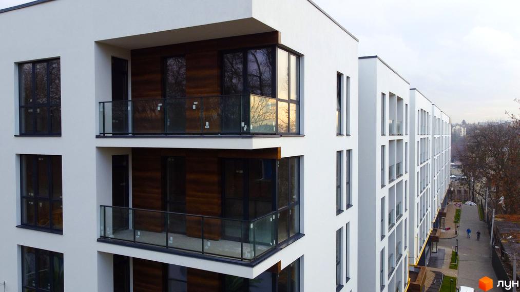 Житловий комплекс Globus Central Park з білими фасадами, скляними балконами та панорамними вікнами. На території комплексу є доріжки для прогулянок.