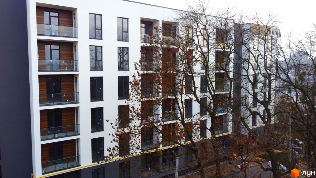 Зовнішній вигляд житлового комплексу Globus Central Park з балконами та вікнами. Навколо будівлі ростуть дерева з червоним листям.