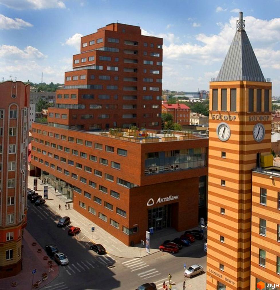 Житловий комплекс БФК „Дом на Катеринославском“ з червоної цегли, прибудинкова територія з автомобілями та зеленими насадженнями.