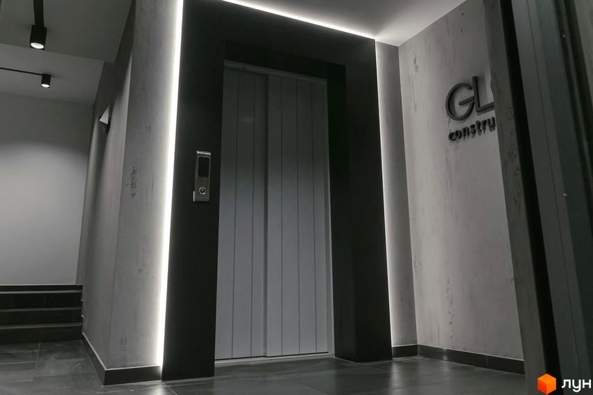 Сучасний вхід до ліфта в житловому комплексі Globus Central Park з підсвічуванням та логотипом забудовника. Стильні двері ліфта та оздоблення стін створюють елегантний вигляд.