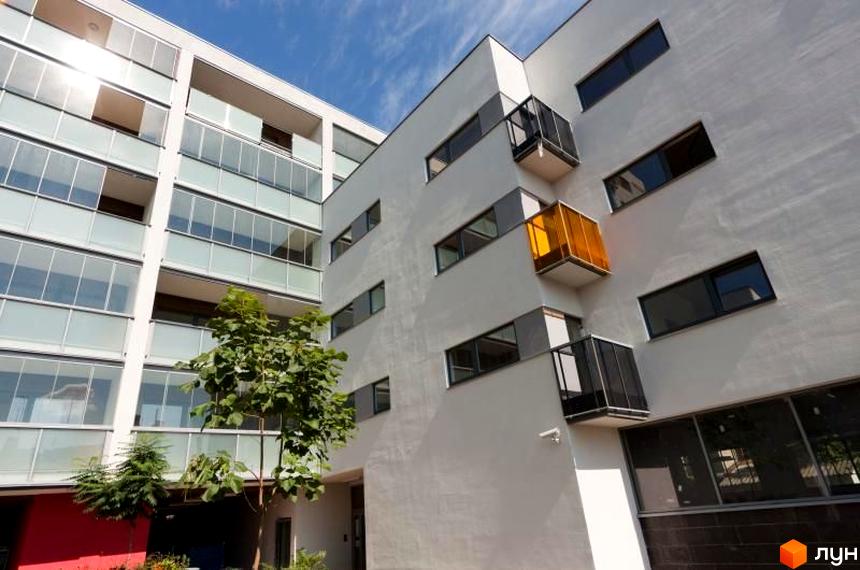 Зовнішній вигляд житлового комплексу ЖК Карат з балконами та зеленими насадженнями на прибудинковій території.