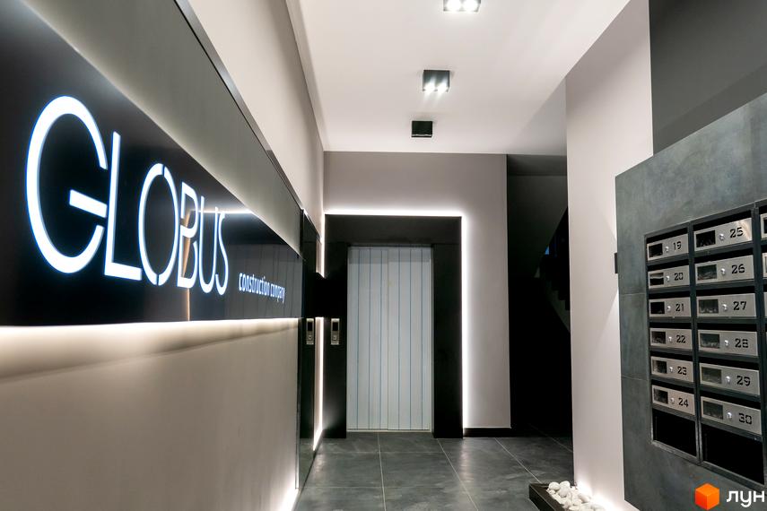 Лобі житлового комплексу Globus Premium з підсвіченим логотипом та поштовими скриньками. Сучасний дизайн вхідної групи новобудови.