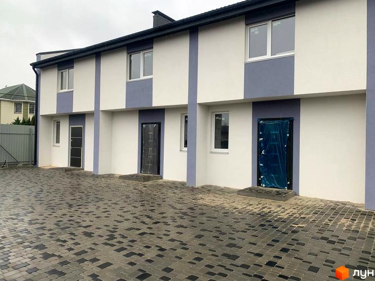 Зовнішній вигляд таунхаусів у Котеджному містечку Smart Country House 2. Фасад будинку з вікнами та дверима, вимощена бруківкою територія.