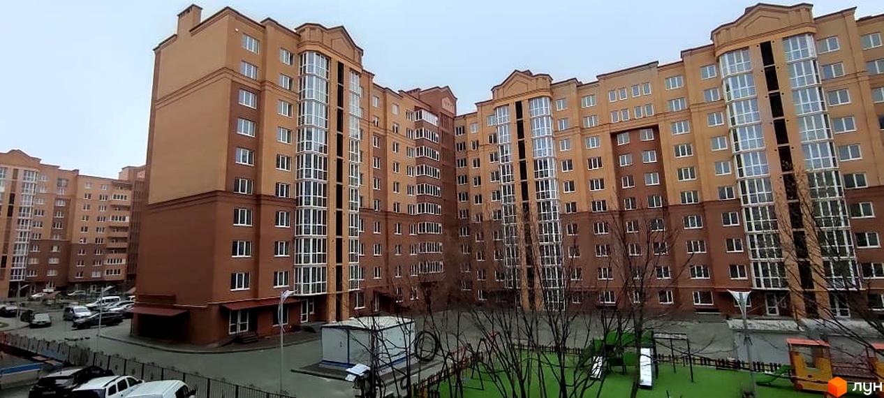 Багатоповерховий житловий комплекс на вул. Київська з коричнево-бежевим фасадом та великими вікнами. У дворі розташований зелений дитячий майданчик та парковка.