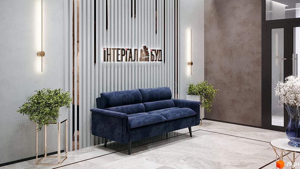 Інтер'єр холу житлового комплексу. Темно-синій диван, рослини у вазонах та декоративне освітлення. На стіні вивіска з назвою ЖК.