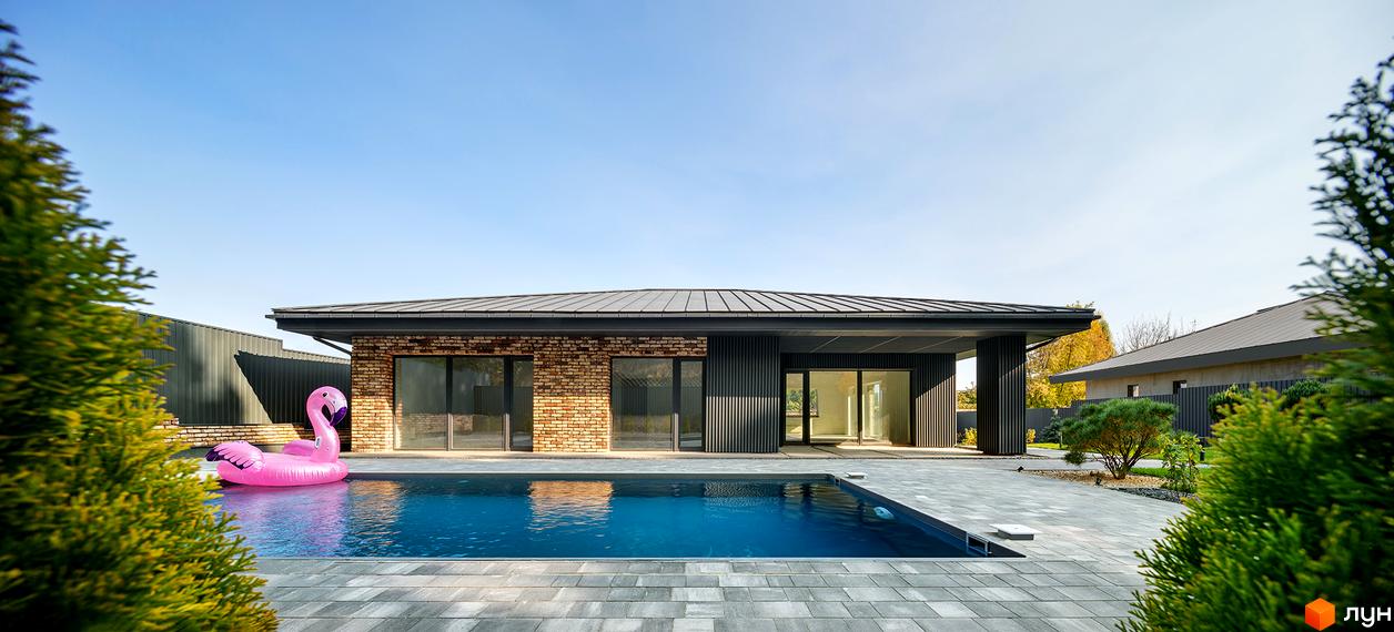 Одноповерховий будинок з басейном та надувним фламінго. Простора прибудинкова територія з бруківкою та зеленню.
