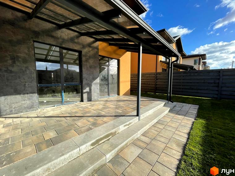 Зовнішній вигляд дуплексів Карамель Сіті з терасою та бруківкою. Прибудинкова територія з газоном та парканом.