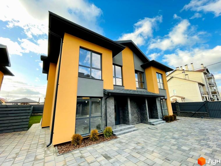 Зовнішній вигляд дуплексів „Карамель Сіті“ з жовто-сірим фасадом та сірим цоколем, розташованих на брукованій прибудинковій території.