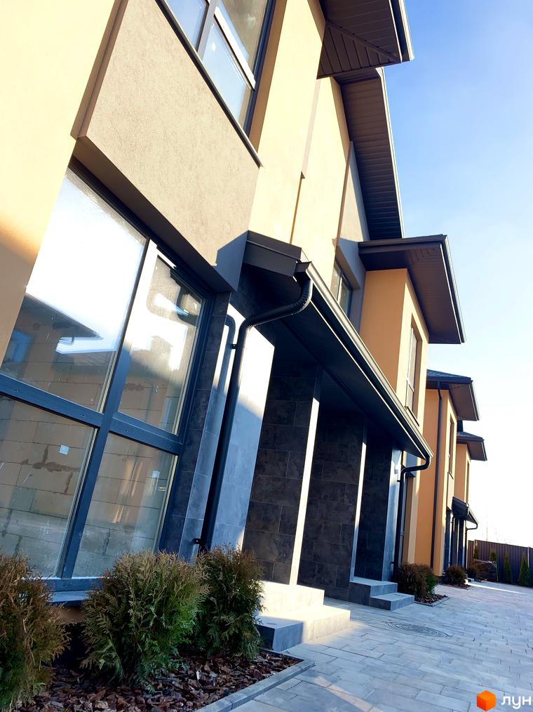 Дуплекси Карамель Сіті – сучасні будинки з великими вікнами та акуратними терасами, розташовані на брукованій прибудинковій території з зеленими насадженнями.