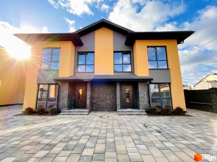 Сучасний дуплекс Карамель Сіті з жовто-сірим фасадом та бруківкою перед будинком. Зовнішній вигляд новобудови та прибудинкової території.