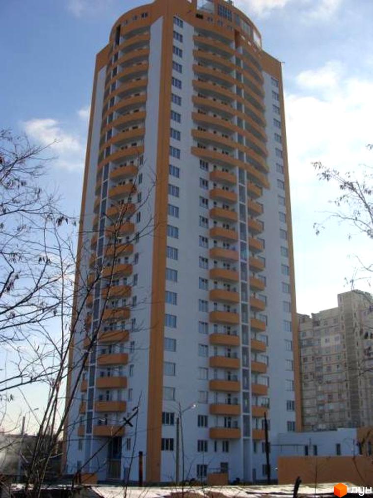 Висотний будинок житлового комплексу Едельвейс з балконами та світлою фасадною частиною. Прибудинкова територія з деревами та освітленням.