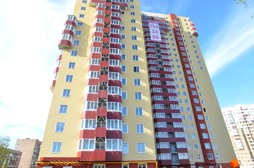 Житловий комплекс Тріумф з фасадом жовтого та червоного кольорів. Прибудинкова територія з зеленими насадженнями.