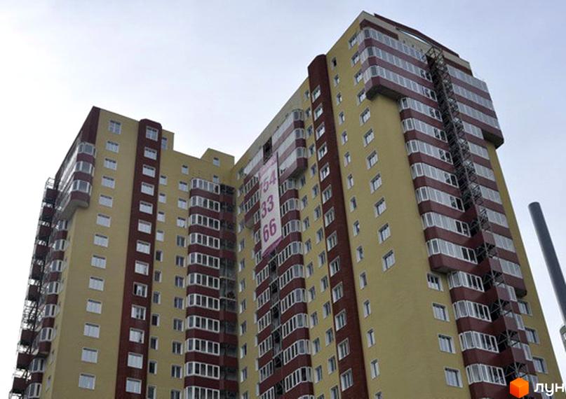 Висотний будинок Житлового комплексу Тріумф з жовтим фасадом та червоними балконами. На будівлі розміщено великий рекламний банер.