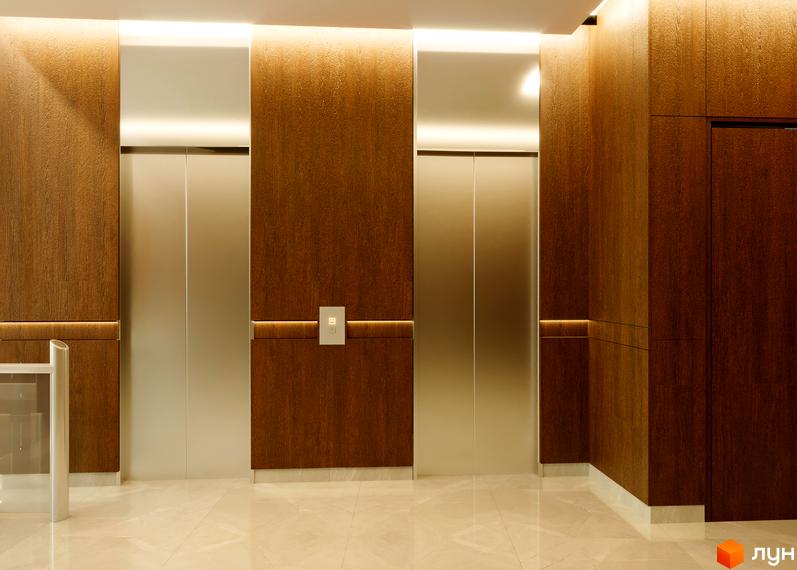 Апарт-готель „На Тургенєвській, 17а“: елегантний хол з двома ліфтами та дерев'яними панелями, що створює затишну атмосферу.