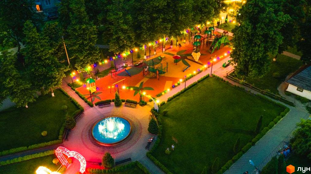 Вигляд зверху на дитячий майданчик та фонтан у Житловому районі Калиновий Квартал. Освітлення додає затишку території.
