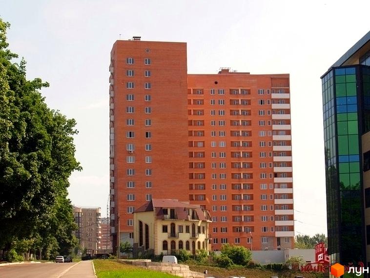 Житловий комплекс ЖК Гранд з червоною фасадною стіною та прибудинковою територією з зеленими насадженнями.